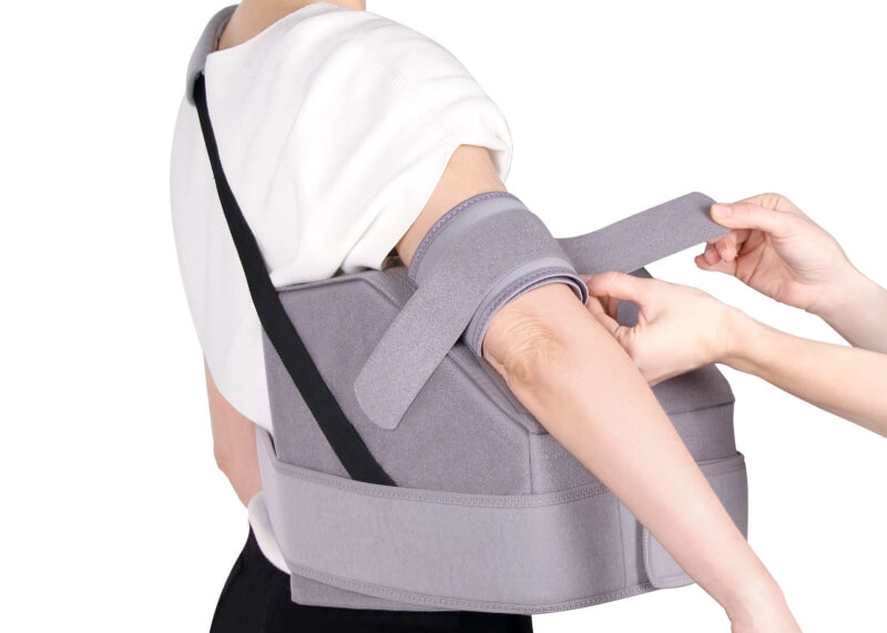 Eine Patientin trägt eine Abduktionsorthese für eine Ruhigstellung mit abgespreiztem Arm