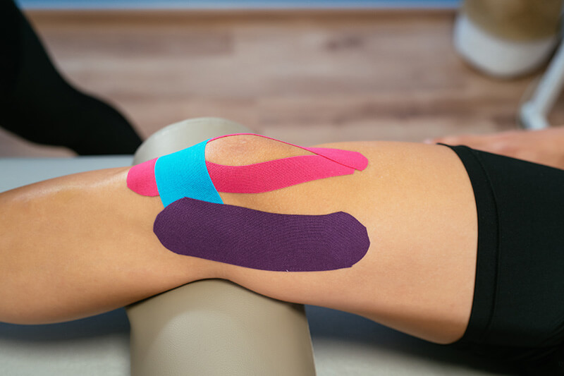 Sporttape kaufen und anbringen Sporttape wird an das Bein einer Person von einem Therapeuten angebracht