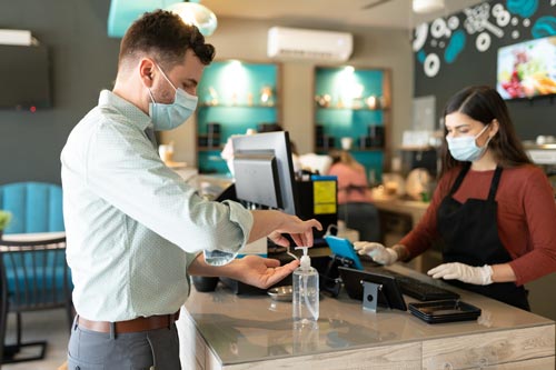 Mann benutzt Hautdesinfektionsmittel im Café