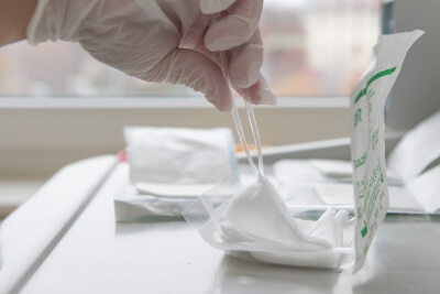 Kompressen für eine hygienische Wundversorgung Ein Arzt holt mit einer Pinzette eine sterile Kompresse aus der Verpackung
